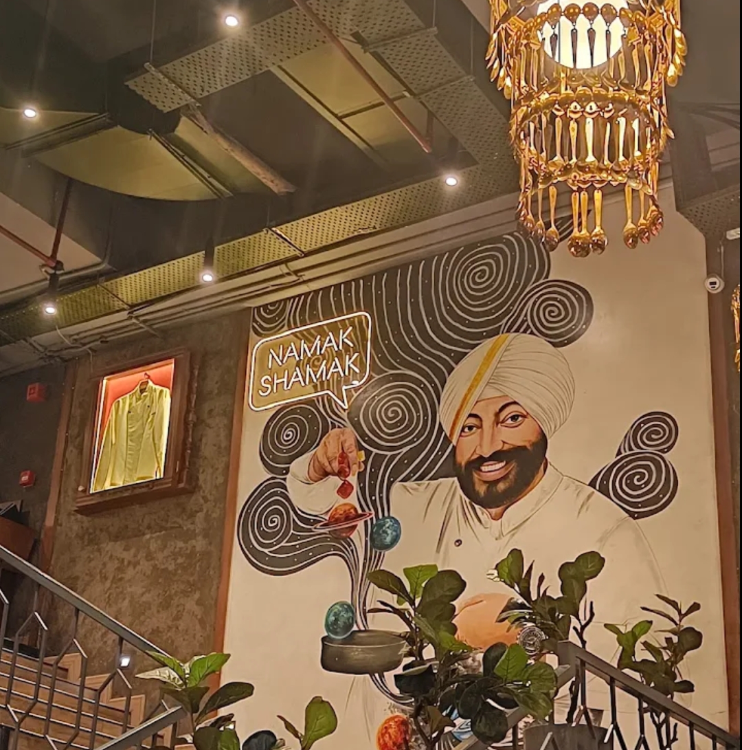 A wall illustration of a turbaned figure beside a neon sign reading Namak Shamak